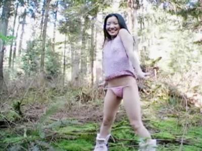 Dünne Asiatin macht sich im Wald nackt